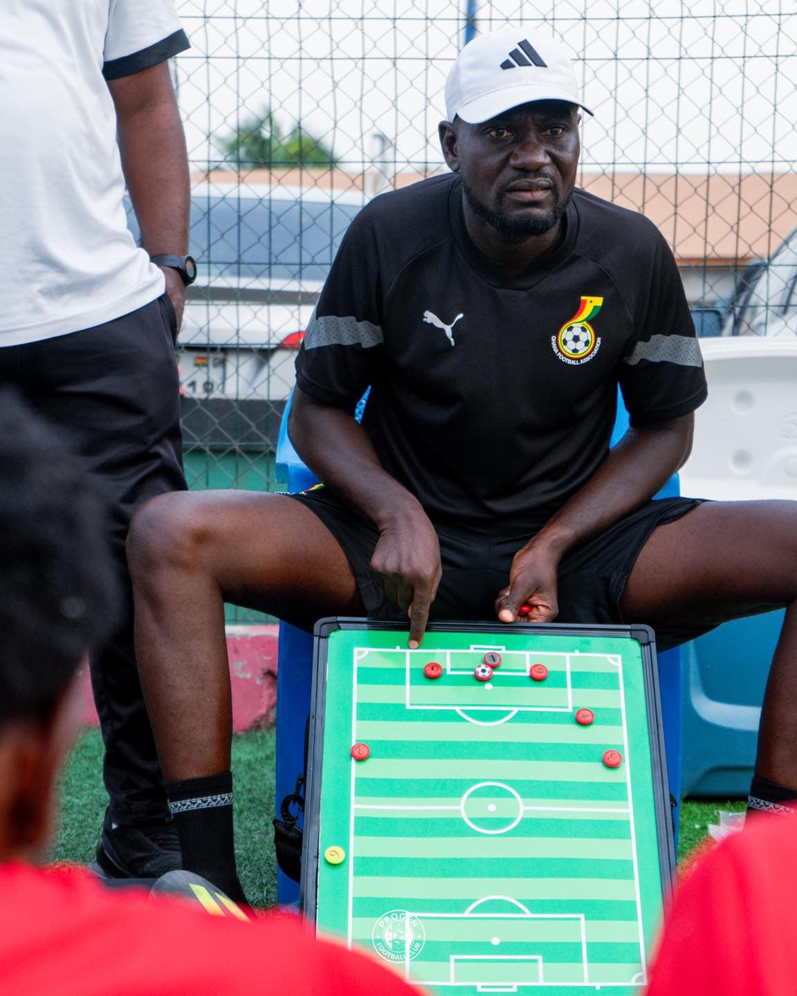 Coach with a tactics board at the side of the pitch